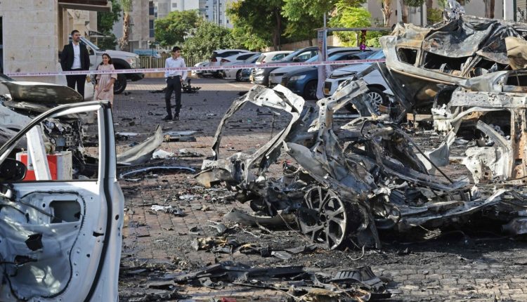 Residents look at the destroyed vehicles in Ashkelon following a rocket attack into southern Israel